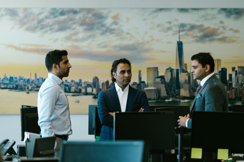 Three businessmen in a meeting with a city skyline background, representing corporate discussion.